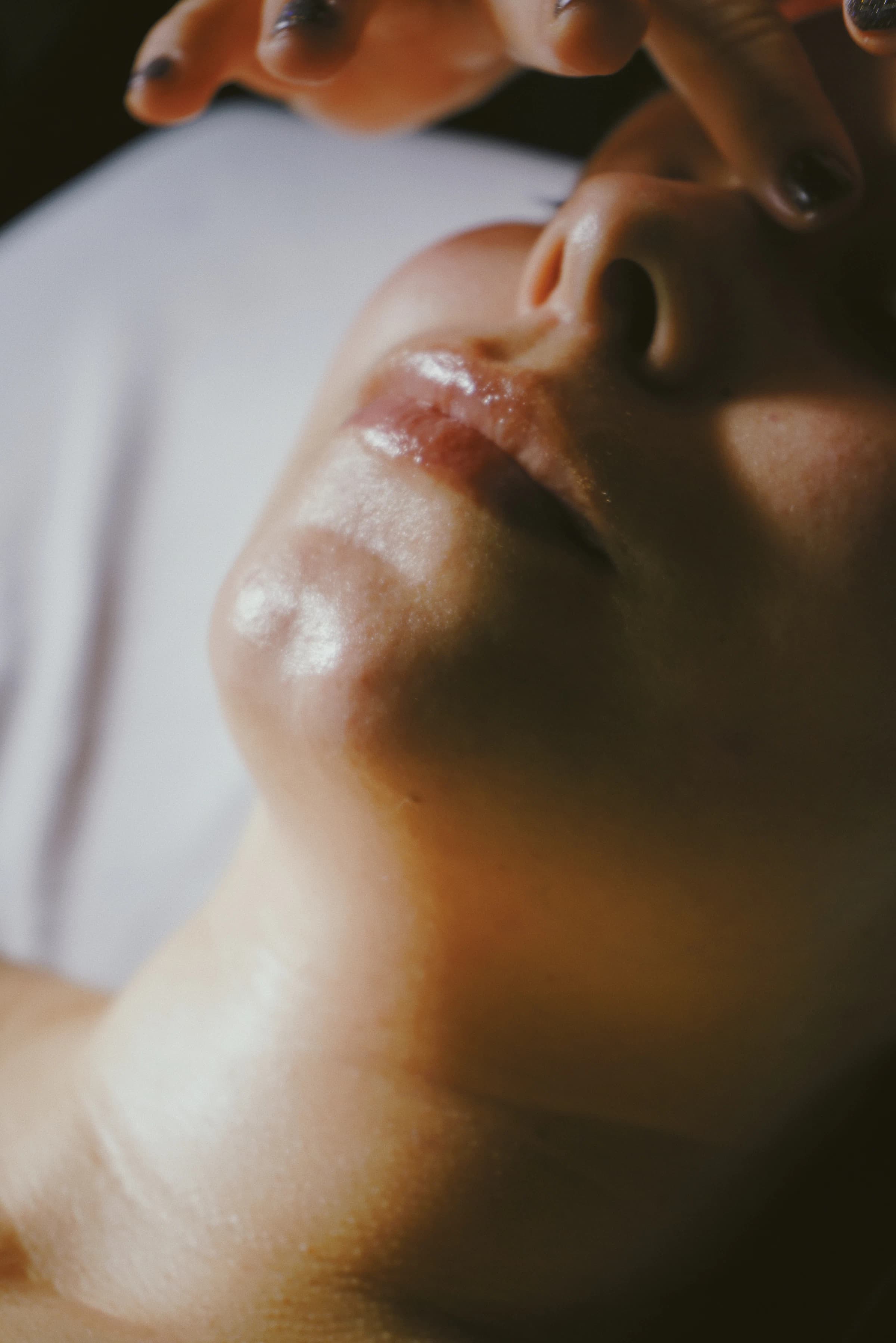 Mains posées sur le visage pendant un soin, dans une lumière chaude